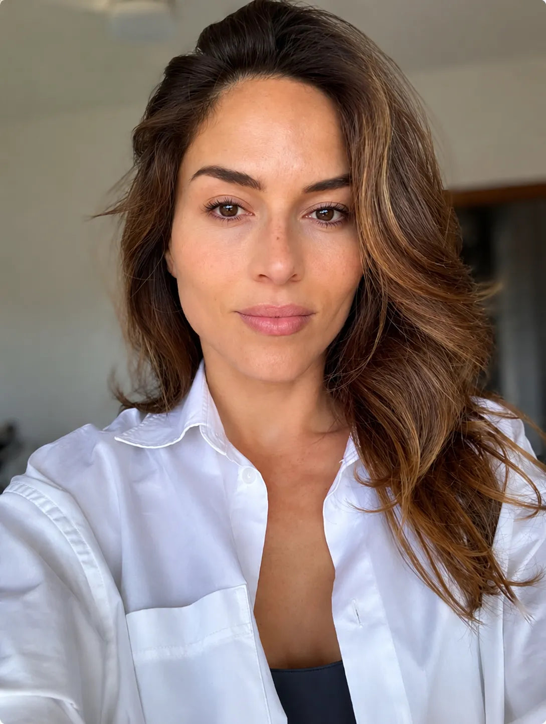 Mujer con cabello castaño y ondas suaves mirando a cámara