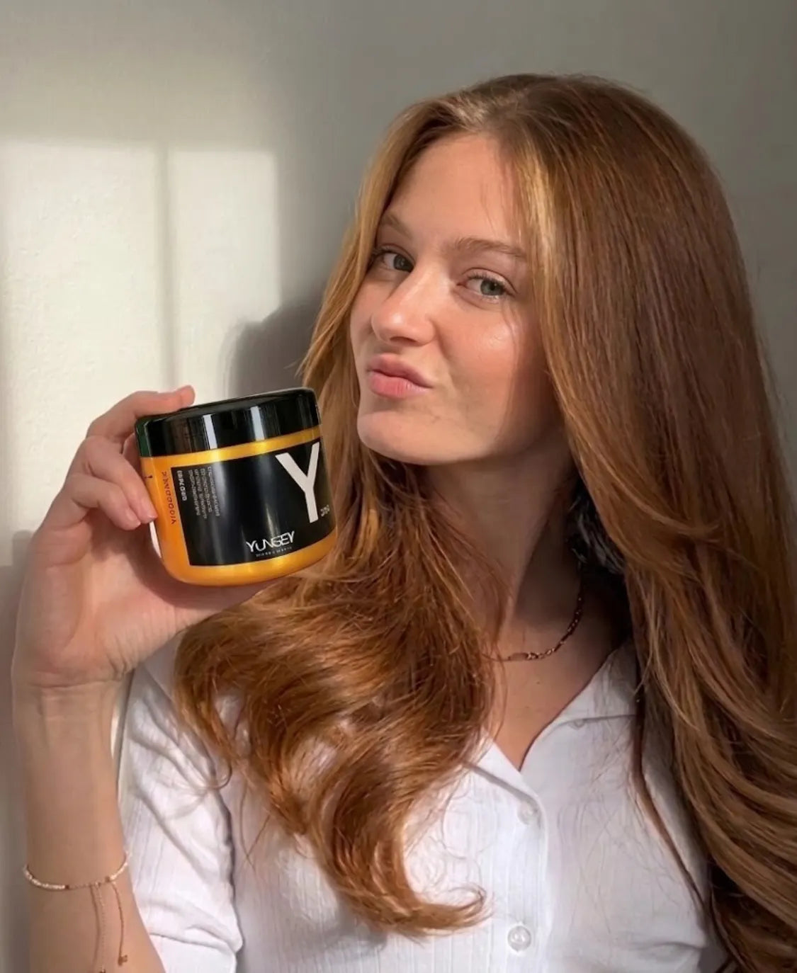 Mujer con cabello largo sosteniendo una mascarilla capilar disponible en PASABELU